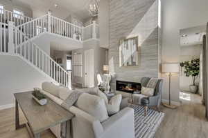 Living room with wood finished floors, stairway, recessed lighting, a towering ceiling, and a tiled fireplace