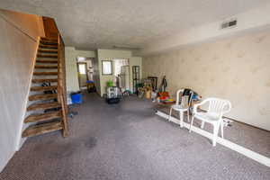 Exercise area with a textured ceiling, wallpapered walls, and carpet flooring