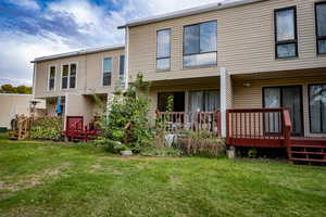 Rear view of property featuring a deck and a lawn