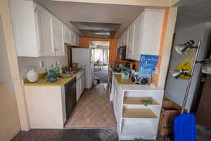 Kitchen featuring white cabinetry, light countertops, white appliances, and light carpet