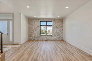 Empty room featuring light wood-style floors, recessed lighting, and a textured ceiling