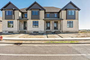 View of front of property featuring stone siding, board and batten siding, and a shingled roof