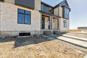 Doorway to property featuring stone siding and a porch