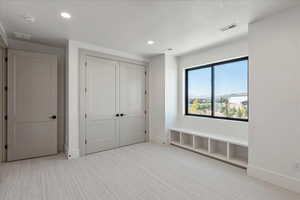 Unfurnished bedroom featuring light carpet, recessed lighting, and a closet