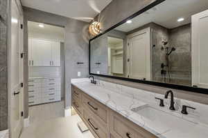 Bathroom with double vanity, a closet, recessed lighting, a tile shower, and light tile patterned floors