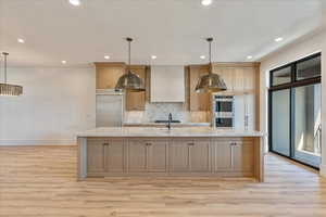 Kitchen with light stone countertops, decorative backsplash, a spacious island, decorative light fixtures, and recessed lighting