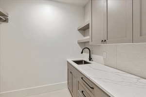 Laundry area with a sink and light tile patterned flooring