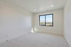 Spare room with a mountain view, light colored carpet, recessed lighting, and a textured ceiling