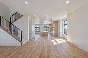 Unfurnished living room with recessed lighting, light wood-style floors, and stairway