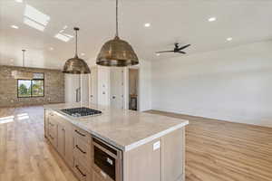 Kitchen featuring open floor plan, a center island, recessed lighting, light wood-type flooring, and decorative light fixtures