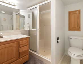 Bathroom featuring vanity, a shower stall, and dark tile patterned flooring