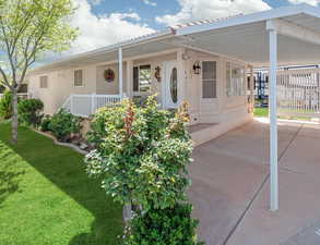 View of front of house with a front lawn, covered porch, and an attached carport