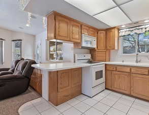Kitchen with open floor plan, white appliances, healthy amount of natural light, and light countertops