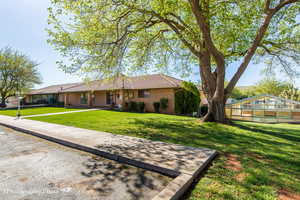 Single story home with a front yard, an exterior structure, a tile roof, and stucco siding