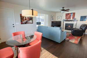Living room featuring wood finished floors, a tiled fireplace, and a ceiling fan