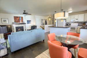 Dining room with dark wood finished floors, a tiled fireplace, and ceiling fan