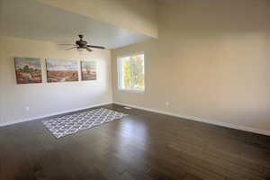 Unfurnished room with dark wood-style flooring and a ceiling fan