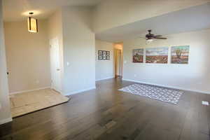 Unfurnished living room featuring dark wood-type flooring and ceiling fan