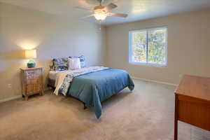 Carpeted bedroom featuring a ceiling fan and baseboards