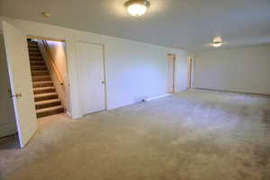 Spare room featuring stairway and light colored carpet