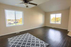 Spare room featuring lofted ceiling, dark wood-style floors, and ceiling fan