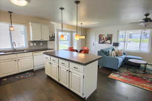 Kitchen with backsplash, dark countertops, white cabinetry, and healthy amount of natural light