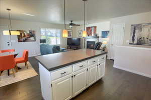 Kitchen with open floor plan, dark countertops, white cabinetry, a kitchen island, and a fireplace