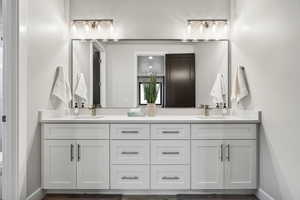 Full bathroom with double vanity and baseboards