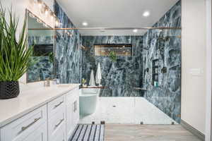 Bathroom with vanity, tile walls, a marble finish shower, recessed lighting, and light wood finished floors