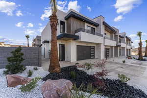 View of front facade featuring a balcony, stucco siding, concrete driveway, and an attached garage