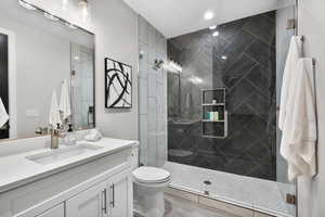 Bathroom featuring vanity and a marble finish shower