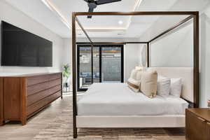Bedroom with ceiling fan, wood finished floors, recessed lighting, and a raised ceiling