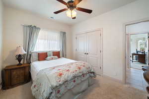 Bedroom with light colored carpet, a ceiling fan, and a closet