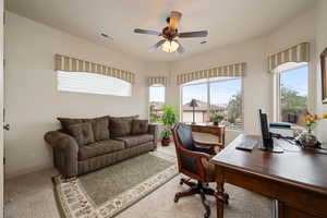 Office area with healthy amount of natural light, ceiling fan, and light carpet