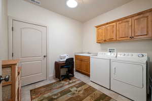 Laundry room with cabinet space, separate washer and dryer, a desk, and light tile patterned flooring