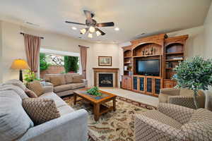 Carpeted living room with a glass covered fireplace, recessed lighting, and a ceiling fan