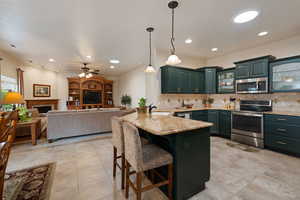 Kitchen featuring glass insert cabinets, a peninsula, a breakfast bar, stainless steel appliances, and hanging light fixtures