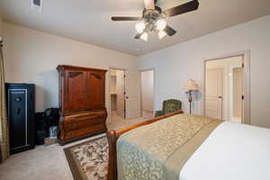 Bedroom with light colored carpet, a spacious closet, and ceiling fan