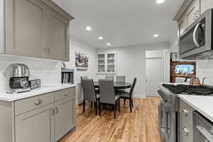 Kitchen with decorative backsplash, stainless steel appliances, recessed lighting, gray cabinets, and light wood finished floors