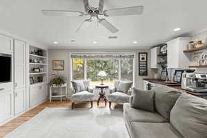 Living area with light wood-style flooring, a textured ceiling, recessed lighting, and crown molding