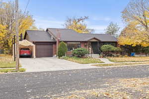 View of front of property featuring roof with shingles, concrete driveway, an attached garage, and a chimney