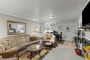 Living room featuring brick wall, a textured ceiling, and wood finished floors