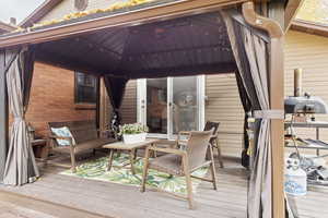 Wooden deck featuring a gazebo and a grill