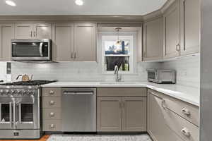 Kitchen with gray cabinetry, stainless steel appliances, backsplash, pendant lighting, and recessed lighting