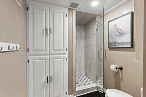 Full bathroom with a shower stall, wooden walls, and ornamental molding