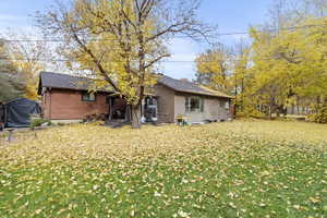 Rear view of house with a yard, a wooden deck, and brick siding