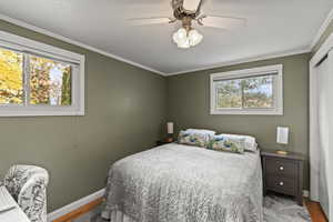 Bedroom with crown molding, ceiling fan, and wood finished floors