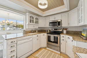 Open kitchen drenched with light and white wood cabinetry.