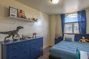 Bedroom featuring dark colored carpet and baseboards