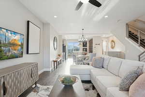 Living area featuring wood finished floors, recessed lighting, stairs, a chandelier, and a ceiling fan